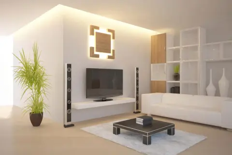 Modernes Wohnzimmer mit indirekter Beleuchtung an der Wand, die eine warme Atmosphäre schafft. Ein Fernseher, weiße Couch und ein Couchtisch sind zu sehen.