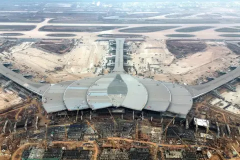 Budowa jednego z nowych lotnisk w Wietnamie. Futurystyczny terminal w kształcie kwiatu lotosu i pasy startowe w tle.