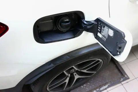Otwarty wlew paliwa w białym Mitsubishi ASX 1.6 benzyna. Widoczny korek i tabliczka informacyjna.