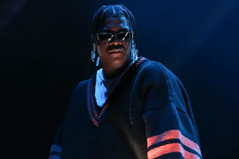 Lil Yachty w Polsce, w okularach i z długimi kolczykami, w swetrze z czerwonymi pasami.