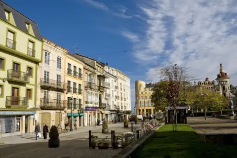 Paseo por el casco antiguo de Ribadeo que ver: fachadas coloridas, balcones de hierro y un cielo azul con nubes.