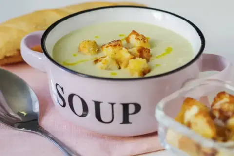 Kremowa zupa z selera naciowego z grzankami w różowej miseczce z napisem "SOUP".