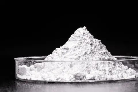 Feiner weißer Pulverberg in einer Petrischale. Dieses Titandioxid ist ein wichtiger Inhaltsstoff in Kosmetikprodukten, z.B. für Sonnenschutz.