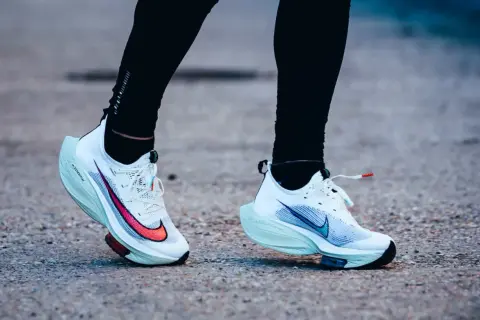 Course sur route avec des chaussures de running blanches dotées d'une plaque carbone.