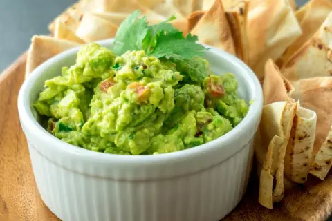 Pyszne guacamole z pomidorami i kolendrą, idealne do szybkiego przygotowania. Podane z chrupiącymi nachos.