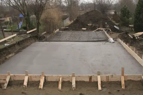 Plac budowy z wylana betonowa płyta fundamentowa i zbrojenie.