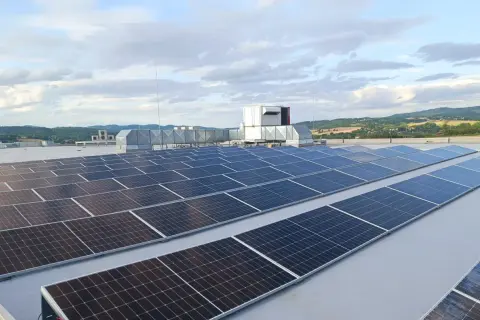 Duże panele fotowoltaiczne na dachu, obok systemów wentylacyjnych i agregatu prądotwórczego, zapewniające niezawodność energetyczną.