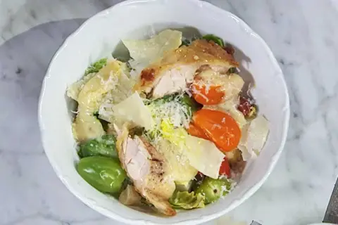 En härlig caesarsallad med kyckling, parmesan och krutonger, generöst täckt med krämig caesarsallad dressing.