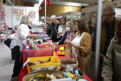 Gente comprando en un puesto de **rastrillo Aragón** con juguetes y libros.
