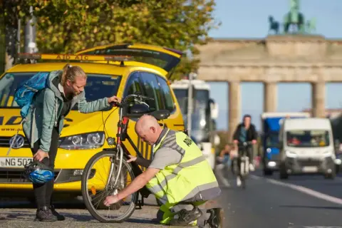 ADAC-Mitarbeiter hilft Frau bei einer **ADAC Fahrradpanne** vor dem Brandenburger Tor.