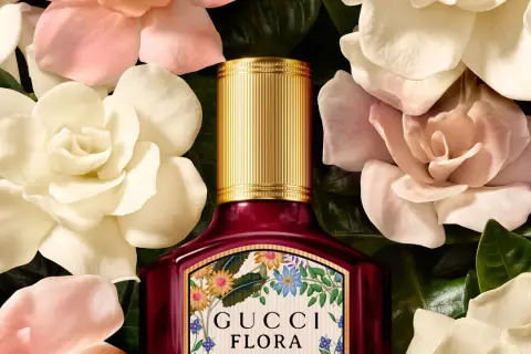 Perfumy Gucci by Gucci Flora w otoczeniu delikatnych kwiatów. Złota nakrętka i bogata etykieta z motywem roślinnym.