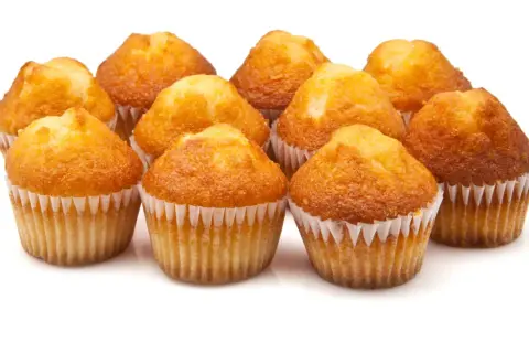Un grupo de magdalenas de naranja recién horneadas, doradas y esponjosas, listas para disfrutar.