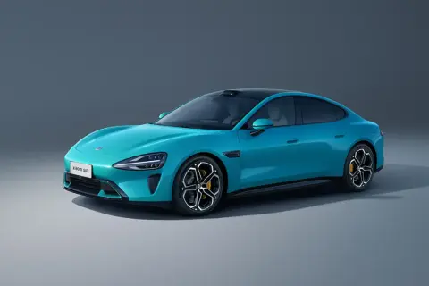 El elegante **Xiaomi SU7** azul turquesa, un sedán eléctrico con líneas aerodinámicas y techo negro, se exhibe sobre un fondo gris neutro.