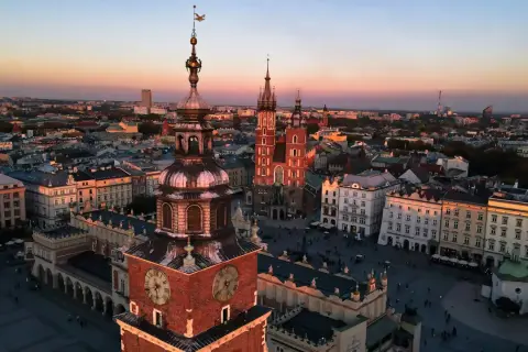 Zachód słońca nad Rynkiem Głównym w Krakowie. Widać wieżę Ratuszową i Kościół Mariacki, ikoniczne kraków zabytki.