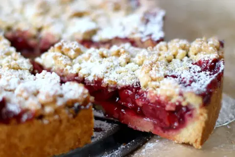 Ein saftiger Kirschkuchen mit knuspriger Streuseldecke, bestäubt mit Puderzucker. Ein Genuss für jeden Kaffeetisch.