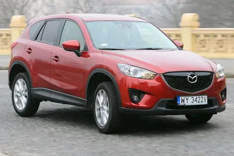 Czerwona Mazda CX-5 na drodze, z widocznym grillem i tablicą rejestracyjną.