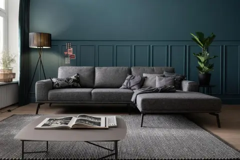Grauer Teppich, heller als die graue Couch, liegt vor einem modernen Sofa mit Kissen.