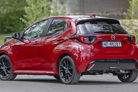 Czerwona Mazda 2 Hybrid widziana z tyłu, z czarnymi felgami i przyciemnianymi szybami.