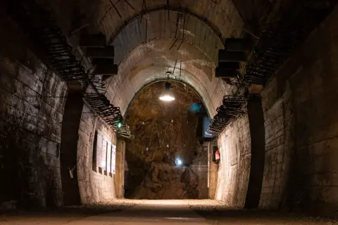 Wnętrze tunelu w Górach Sowich. Betonowe ściany, łukowe sklepienie i oświetlenie tworzą mroczny klimat.