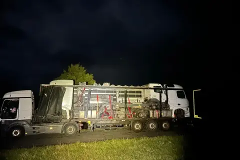 Nocą na poboczu stoi nietypowy pojazd nienormatywny, przewożący elementy maszyn.