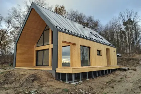 Nowoczesny dom drewniany 70m2 pod klucz, z dużymi oknami i tarasem, otoczony lasem.