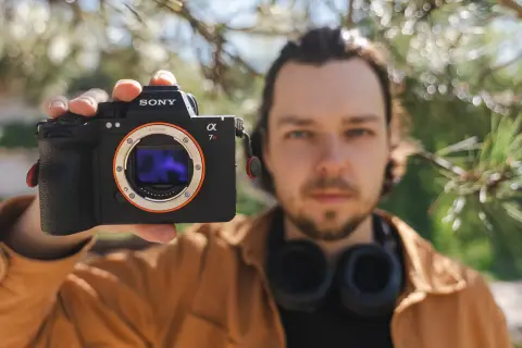 Mężczyzna prezentuje aparat Sony a7riv z obiektywem E-mount.