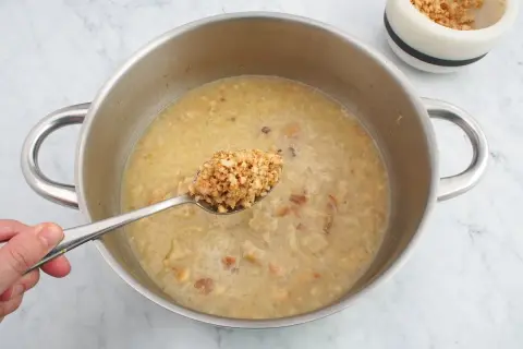 Cuchara con trozos de almendras listas para añadir a la salsa en la olla.