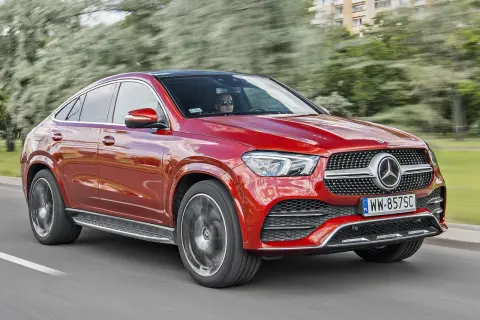 Czerwony Mercedes-Benz GLE Coupe, model gle amg, pędzi po drodze, za kierownicą siedzi kierowca w okularach.