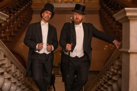 Zwei Herren im eleganten Frack mit Zylinder und Gehstock, ein perfektes Beispiel für den Dresscode Herren für einen besonderen Anlass.