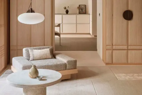 Gemütliches Wohnzimmer im Japandi Stil mit Sofa, Couchtisch und Holzelementen.