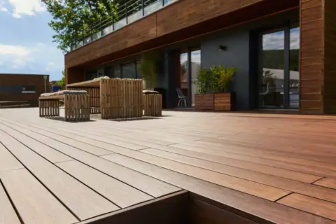 Terrazza in legno con mobili da esterno. La posa a secco, meglio sabbia o ghiaia, garantisce stabilità e drenaggio.