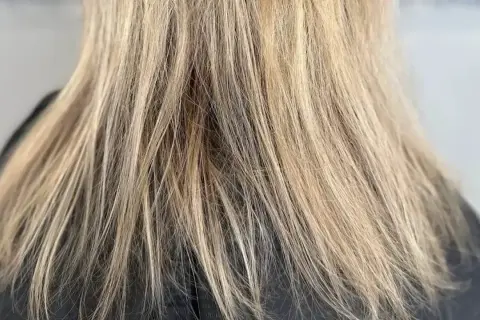 Nahaufnahme von schlecht blondierten Haaren mit ungleichmäßigen Blondtönen und sichtbaren Ansätzen.