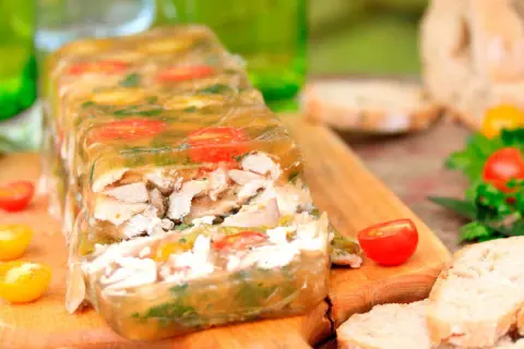 Un appétissant lapin en gelée, garni de tomates cerises et d'herbes, prêt à être dégusté avec du pain frais.