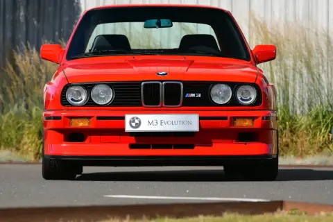 Roter BMW E30 M3 Evolution, ein Klassiker aus den 80ern, steht im Freien.