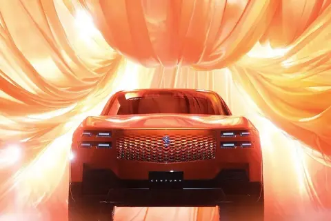 Nowy Toyota Century w pomarańczowym odcieniu, otoczony falującymi, złotymi tkaninami, prezentuje swoją luksusową kratę i reflektory.