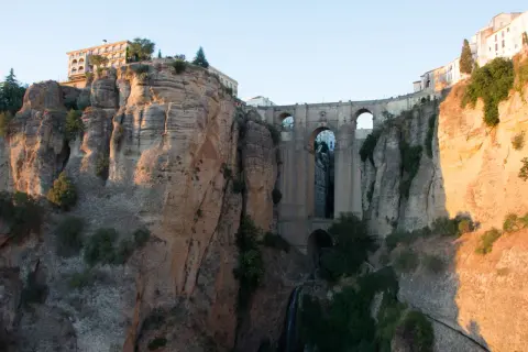 Impresionante puente de piedra sobre un profundo tajo, ideal para rutas por Ronda. Edificios se asoman al abismo.