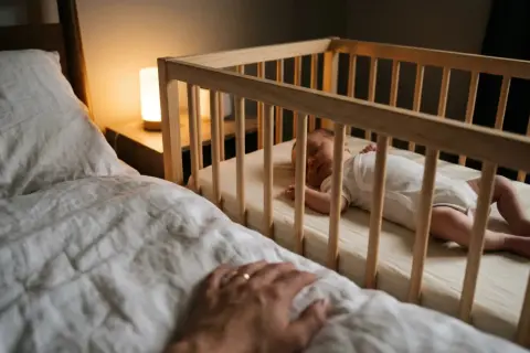 A peaceful baby sleeps in a mini crib. Parents check the mini crib weight limit to ensure safety as their little one grows.