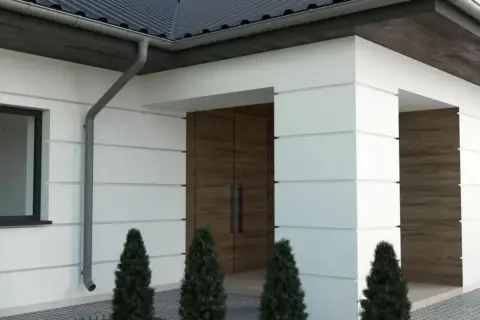 Nowoczesny dom z białymi boniami, drewnianymi drzwiami i ciemnym dachem.