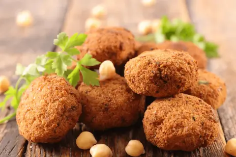 Polpette dorate e croccanti, perfette polpette senza uova, guarnite con prezzemolo fresco e ceci su un tagliere di legno.