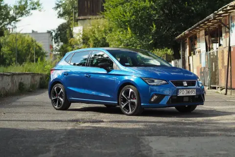 Niebieski Seat Ibiza na tle zieleni i budynków. Poznaj jego seat ibiza dane techniczne.