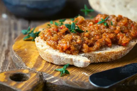 Pyszna pasta z bakłażana na chrupiącym pieczywie, ozdobiona świeżymi ziołami. Idealna na przekąskę.