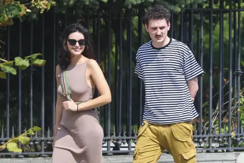 Dawid Podsiadło i jego dziewczyna spacerują w słoneczny dzień. Ona w beżowej sukience, on w bluzie w paski.