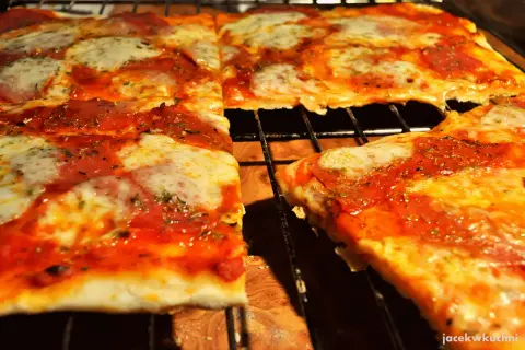 Pyszna pizza na cienkim cieście, z ciągnącym się serem i aromatycznym sosem pomidorowym, prosto z pieca.