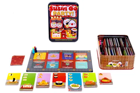 Gra karciana Sushi Go Party! z kolorowymi kartami i planszą. Pudełko z grą i pojemnik pełen kart.