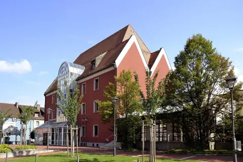 Das Handwerksmuseum Deggendorf präsentiert sich in einem modernen Gebäude mit auffälliger Glasfront und roten Fassaden.