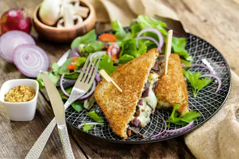Un délicieux croque monsieur végétarien garni de champignons et de fromage fondant, servi avec une salade fraîche et de la moutarde à l'ancienne.