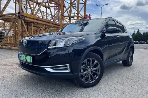 Czarny, lśniący SUV, jeden z chińskich samochodów elektrycznych, zaparkowany na tle budowy.