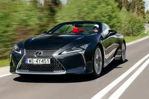 Czarny kabriolet Lexus LC 500 z czerwonym wnętrzem sunie po krętej drodze, zapewniając czystą przyjemność z jazdy i poczucie lexus relax.