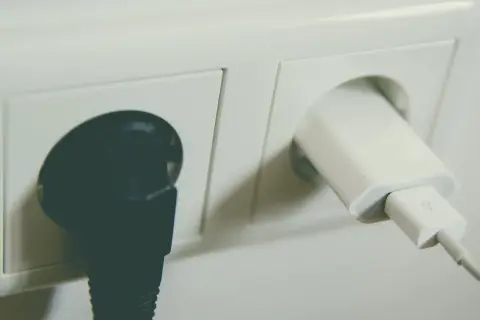 Dwa gniazdka elektryczne: jedno z czarną wtyczką, drugie z białą ładowarką USB. Sprawdź montaż gniazdka cena.
