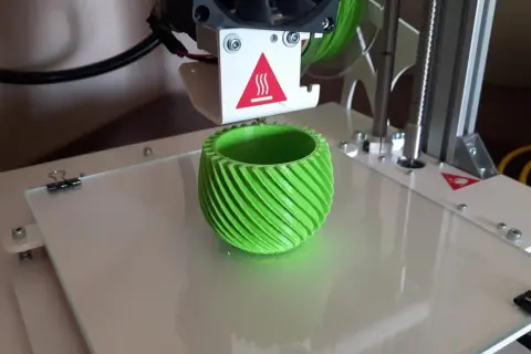 Drukarka 3D drukuje zielony, spiralny wazon.